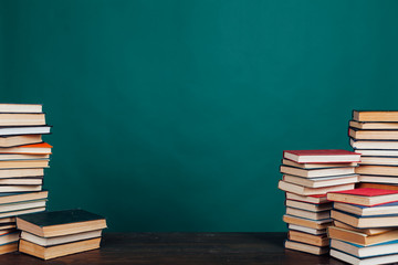 many stacks of educational books to teach in the school library on a green background