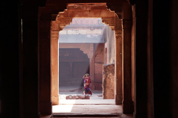 Unidentified indian woman in beautiful sari walks in magic light of Fatehpur Sikri Palace