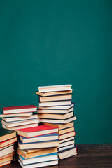 many stacks of educational books to teach in the school library on a green background
