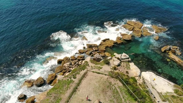 Sydney Coogee beach lookout, drone coming down pan up to ocean, turquoise sea crashing against rocks