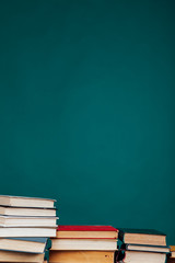 many stacks of educational books to teach in the school library on a green background