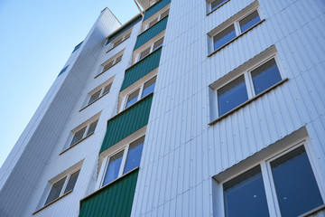 facade of a new multi-storey building with white and green metal siding, many Windows