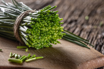Bunch of freshly cut chives wrapped by a jute twine on a vintage wood and chopping board