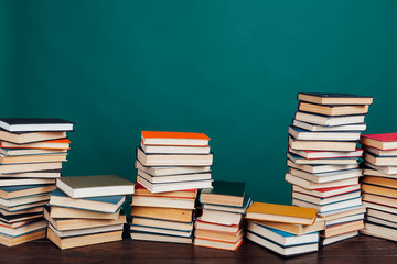 many stacks of educational books to teach in the school library on a green background