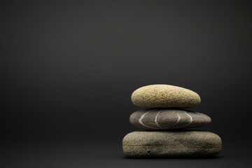 Three stones are stacked isolated on a black background. Zen stone. Arrangement, beauty