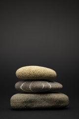 Fototapeta na wymiar Three stones are stacked isolated on a black background. Zen stone. Arrangement, beauty