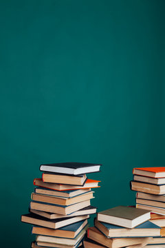 many stacks of educational books to teach in the school library on a green background