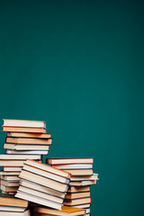 many stacks of educational books to teach in the school library on a green background