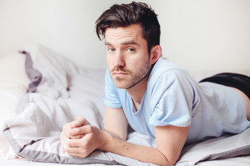 Handsome man in bed looking bored and sad