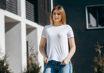 Girl wearing white t-shirt posing against street , urban clothing style. Street photography