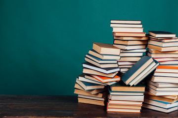 many stacks of educational books to teach in the school library on a green background