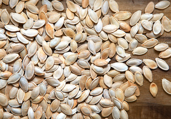 Roasted pumpkin seeds scattered on a wooden background. Close up