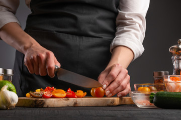 Cooking StirFry vegetables with shrimp. Chef slices cherry tomatoes, on a gray background with shrimp. Seafood