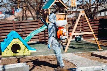 Specialist in hazmat suits cleaning park, disinfecting and decontaminating. Coronavirus quarantine state of emergency