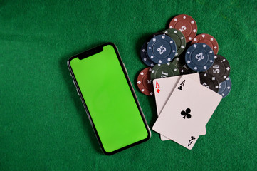 Poker background - chips, cards and phone with a green screen on green table.