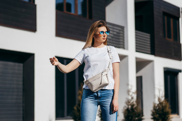 Young model girl in white t-shirt and glasses with waist bag