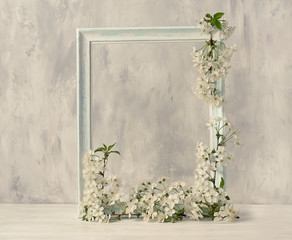 Delicate vintage white frame with vibrant cherry blossoms on a light gray background. Spring background.