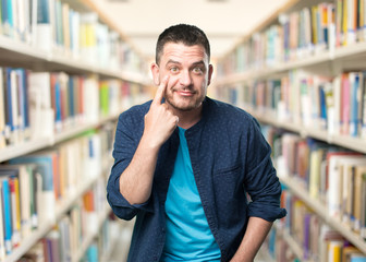 Young man wearing a blue outfit. Pointing to his eye.