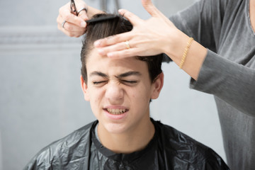 Son in pain while his mother cuts his hair at home