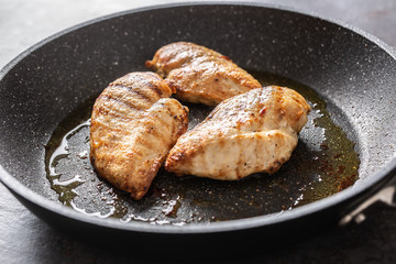 Pan-fried juicy chicken breasts on a dark pan