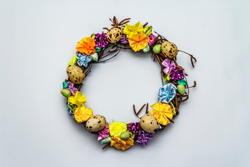Hand crafted Easter wicker wreath with quail eggs and handmade flowers. Birch branches, polka dot satin ribbon. Stay at home concept. Festive Easter background