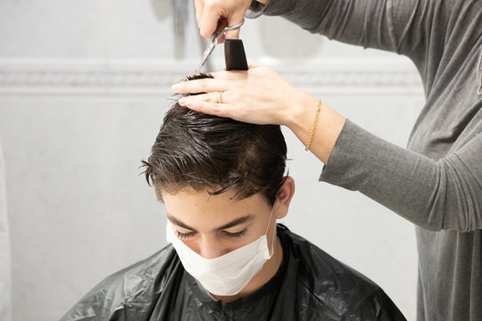 Son With Facial Mask While His Mother Cuts His Hair At Home