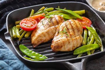 Healthy diet grill pan chicken with green peas and tomatoes close up
