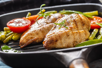 Healthy home cooking, grill pan chicken with green peas and tomatoes and rosemary close up