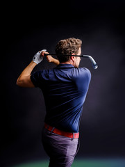 Close-up of a golf player intent on perfecting the swing isolated on dark background