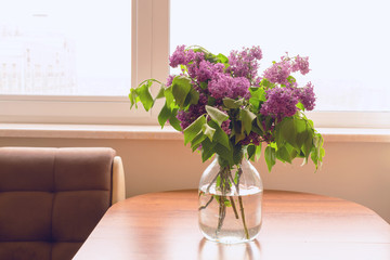 Beautiful bouquet of lilacs on a table by the window. Rustic spring background