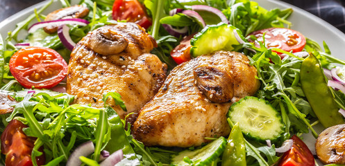 Close up of a healthy fresh salad with grilled chicken breasts and mushrooms on a plate