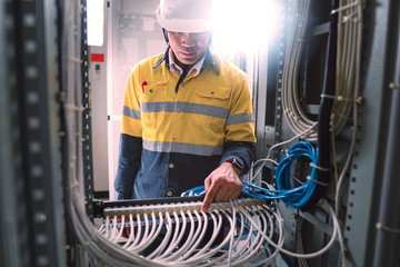 Engineer in yellow uniform, wearing a white safety helmet, checking communication system, big data...