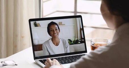 Over shoulder view of female psychologist consulting african woman client during online counseling therapy session using computer video call distance web cam chat app concept. Laptop screen closeup. - Powered by Adobe