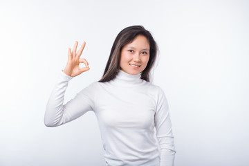 Photo of smiling female student is showing ok gesture on white background.
