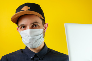 Businessman in a medical mask looks at the news on his laptop. Men works at home, self-isolation, quarantined from coronavirus.