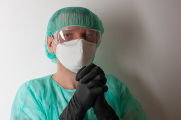 Male nurse, with plastic protective eyeglasses and respirator ffp2, cap, gown, gloves,  with  personal protective equipment to protect against the virus covid-19 in ICU in hospital.