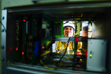 Engineer in yellow uniform, wearing a white safety helmet, checking communication system, big data concept