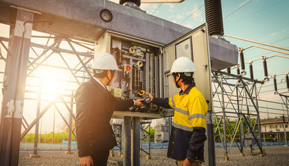 Businessmen and engineers are talking about problems and electricity production in large power plants, dem uses a multimeter to check for problems