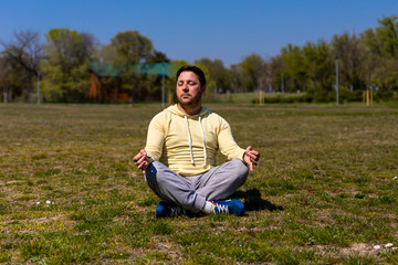 Naklejka na ściany i meble Man practicing Yoga in park. Meditation and zen relaxation in nature