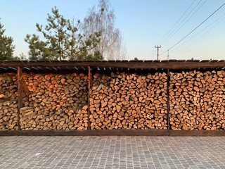 Chipped dry firewood is ready for winter. Background of logs, birch, pine and oak. A wall of...