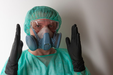 Male nurse, with twin filter half face respirator mask , cap, gown,  with  personal protective equipment to protect against the virus covid-19 in ICU in hospital.