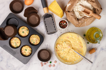 Preparation homemade Savory muffins with Parmesan cheese, sausage or ham and green peas for Breakfast. Flour, eggs and other ingredients on the marble table . Selective focus