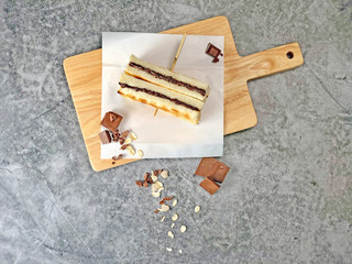 Baked chocolate cereal toast is set on a white baking paper and beautifully textured cutting board. It is paired with chocolate chips. Oatmeal. Beautiful gray texture background.