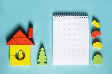 A house made of blocks on a blue background. Flat lay with an inspired quote, staying at home...