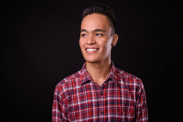 Face of happy young Indian hipster man thinking