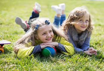 Two girls lie on grass