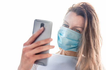 Woman wearing medical face mask holding ohone outdoors. Covid-19 outbreak pandemic.
