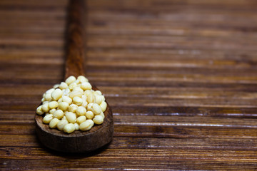 White lentils on a spoon with a wooden background