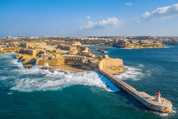 Aerial  view of red lighthouse and Fort Ricasoli. Big stormy waves, Mediterranean sea. Malta 