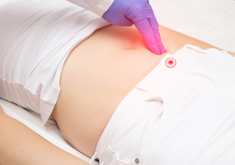 A traumatologist doctor examines the lower abdomen of a girl who has a blunt abdominal injury.